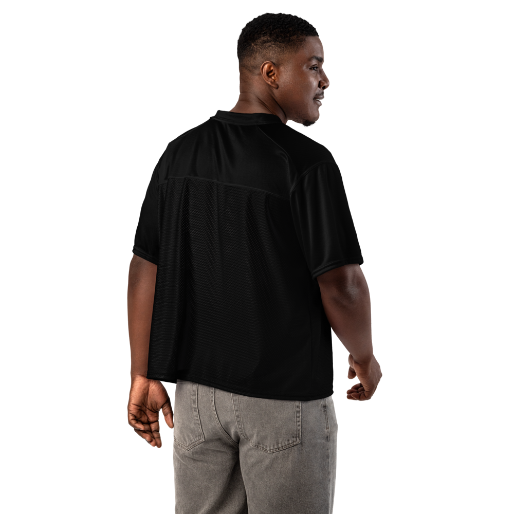 A man wearing facing forward showing a black short-sleeve athletic, street wear, or rave jersey, shown from the back and side profile against a solid white background.